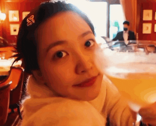 a close up of a woman 's face while holding a glass of beer