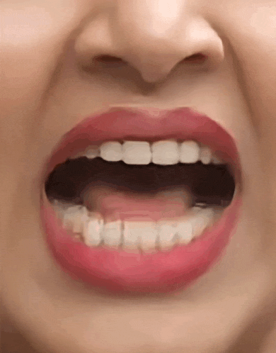 a close up of a woman 's mouth with her mouth open and red lips .