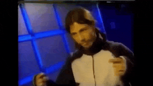 a man in a black and white jacket is dancing in front of a blue background .