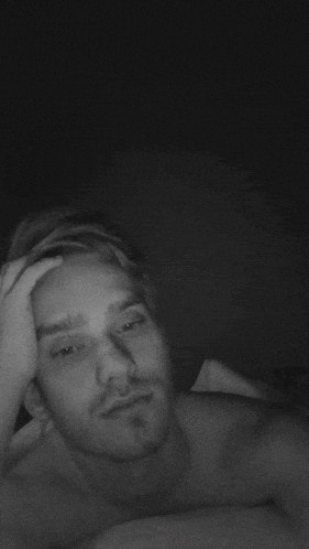 a black and white photo of a shirtless man making a heart shape with his hands