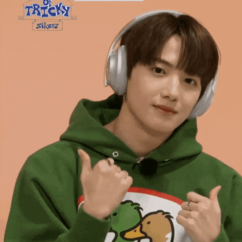 a boy wearing headphones and a green hoodie with tricky stickers written on it