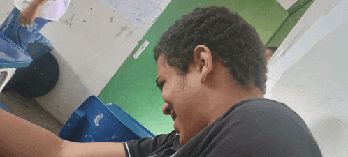 a man in a black shirt is sitting in front of a blue bin