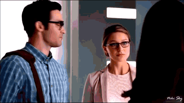a man and a woman are standing next to each other and the woman is wearing glasses and a white shirt