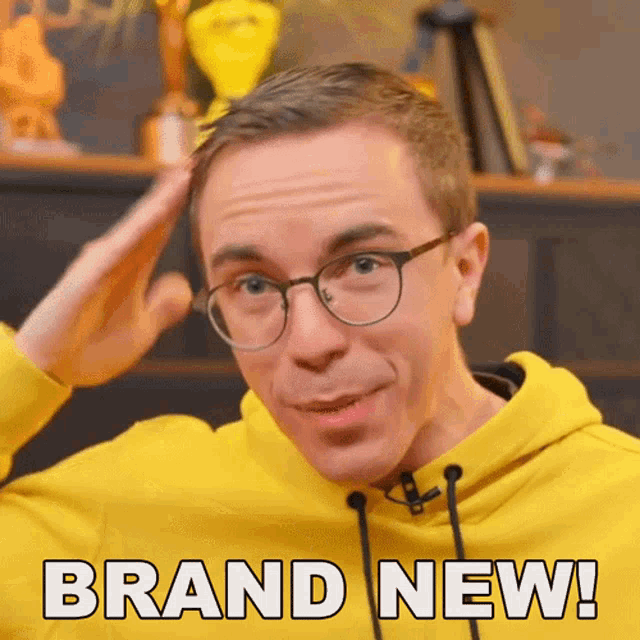 a man wearing glasses and a yellow hoodie has the words brand new on his face