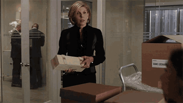 a woman standing next to a cardboard box that says diane lockhart on it