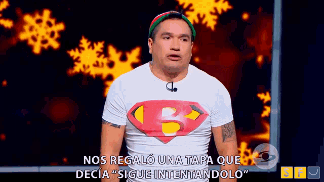 a man wearing a superman t-shirt is standing in front of a snowflake background