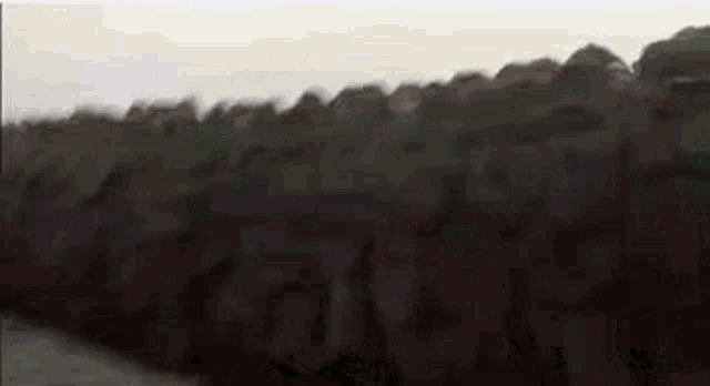 a group of people standing on top of a hill with a smoke coming out of it .