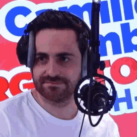 a man wearing headphones stands in front of a microphone in front of a sign that says comm bank