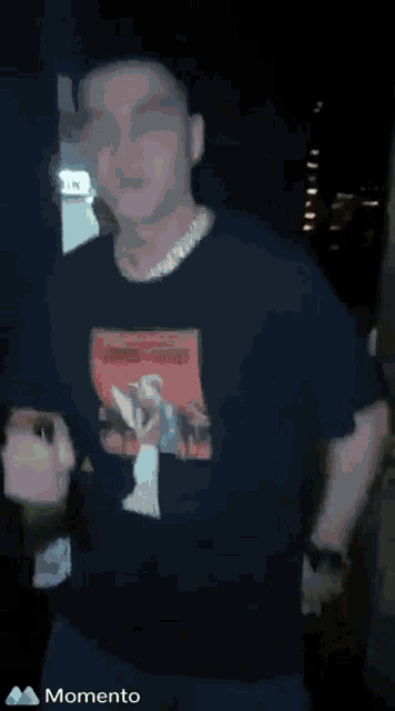a man wearing a black shirt that says romeo juliet is holding a bottle of wine .