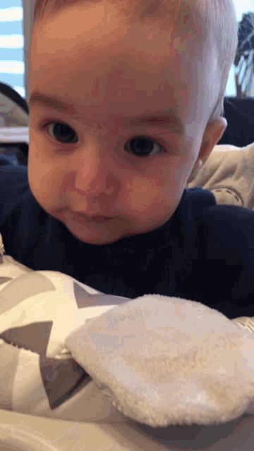 a baby laying on a blanket with a white towel
