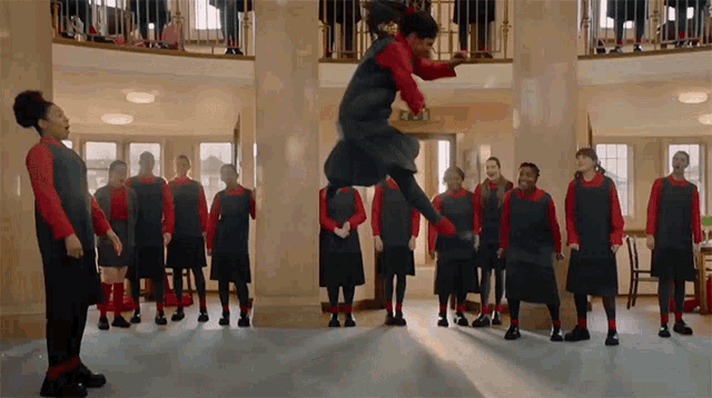 a girl is jumping in the air in front of a group of children