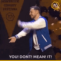 a man in a blue varsity jacket is dancing on a stage in front of balloons .