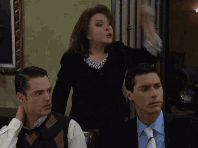 two men and a woman are sitting in a room with a woman standing behind them