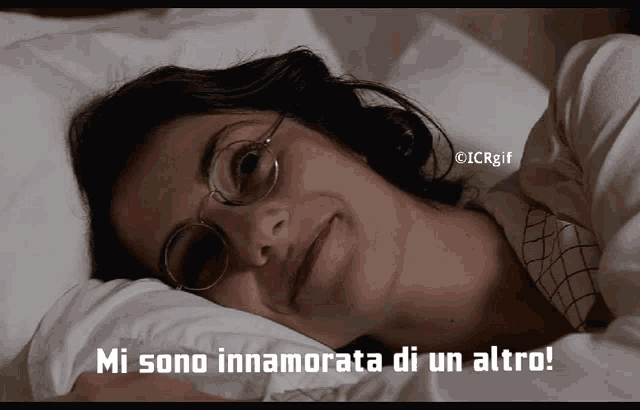 a woman wearing glasses is laying in bed with the words mi sono innamorata di un altro written below her