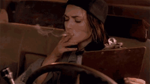 a woman is smoking a cigarette while driving a car