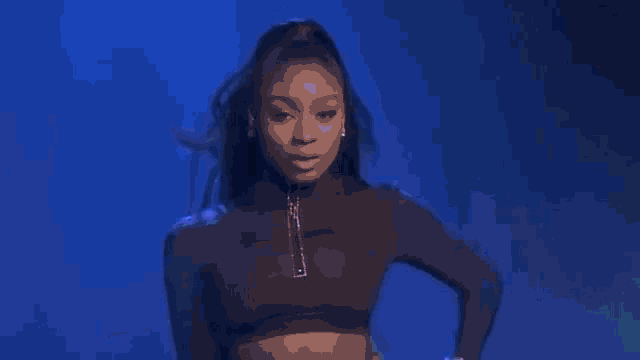 a woman is singing into a microphone on a stage with blue lights .