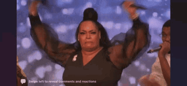 a woman in a black dress is dancing on a stage while a man holds a microphone .