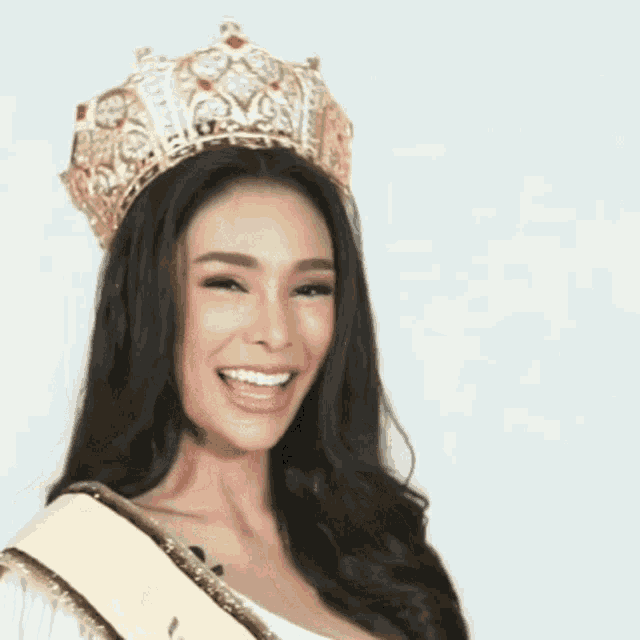 a woman wearing a crown and a sash smiles