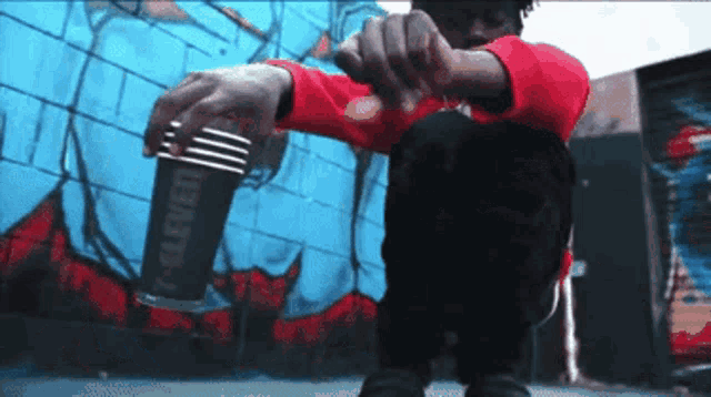 a man in a red shirt is kneeling down in front of a wall that says eleven
