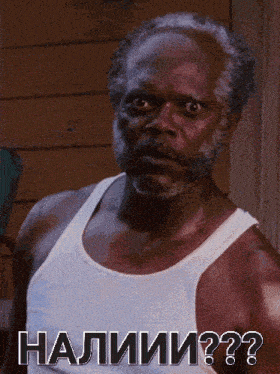 a man with a beard wearing a white tank top with the words " halimi " on the bottom