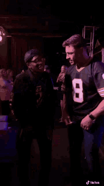 a man in a number 8 jersey stands in a crowd of people