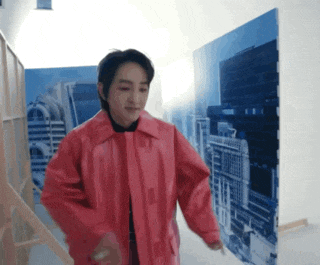 a man in a red jacket is dancing in front of a large picture of a city .