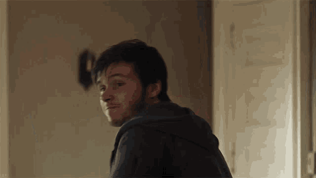 a man with a beard is looking at the camera in a room