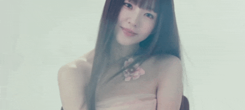 a woman with long hair and a flower tattoo on her chest is smiling .