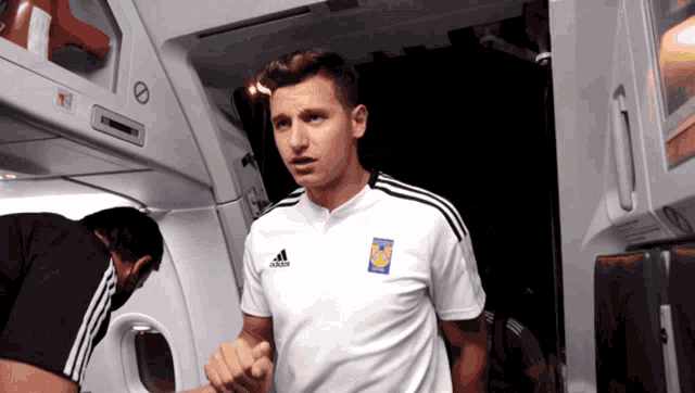 a man wearing a white shirt with the word adidas on the front
