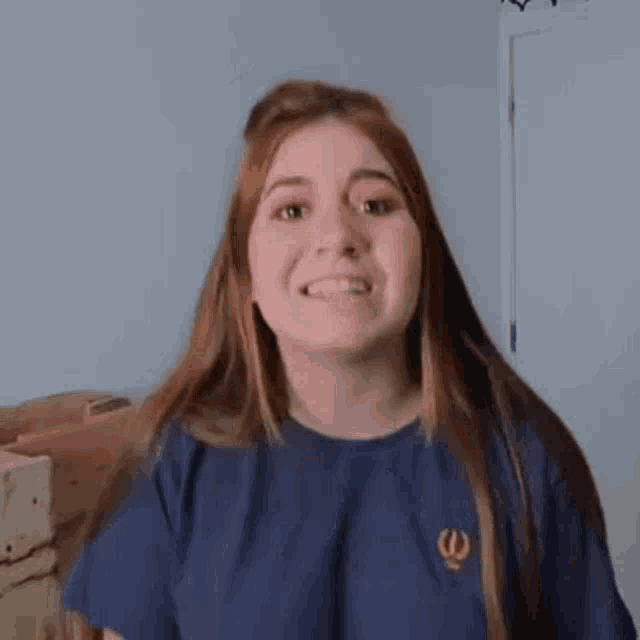 a woman in a blue shirt is making a funny face with her mouth open .