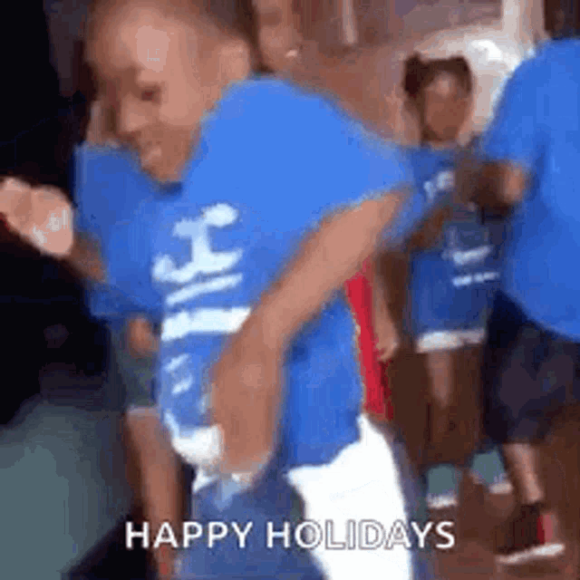 a young boy in a blue shirt is dancing in front of a crowd of people .
