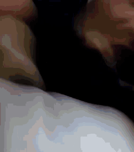 a close up of a person laying on a bed with a black background