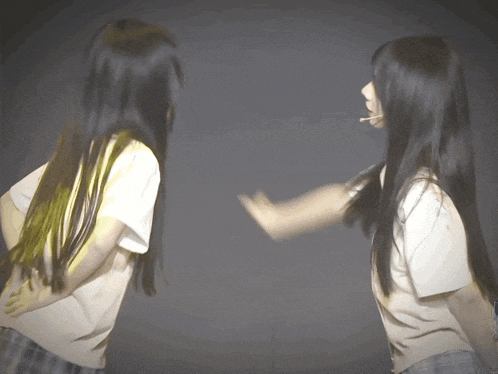 two girls with long black hair are dancing together