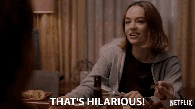 a woman sitting at a table with a netflix logo on the bottom