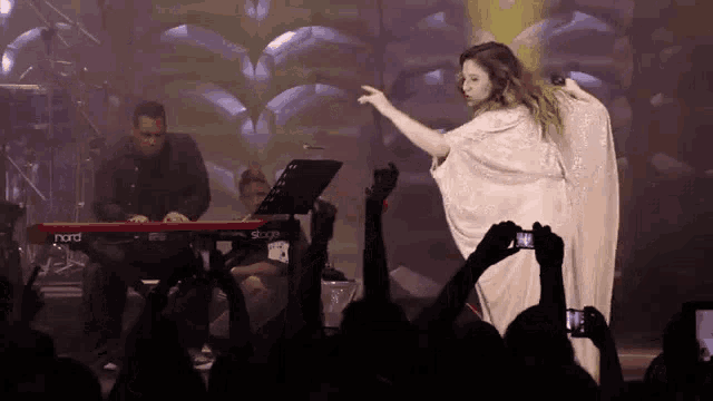 a woman in a white dress stands in front of a nord stage