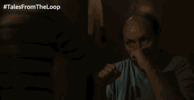 a man wipes his nose in a dark room with #talesfromtheloop written on the bottom