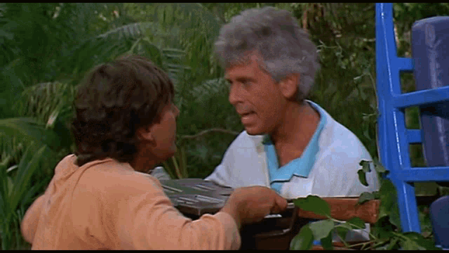 two men are talking to each other in a jungle