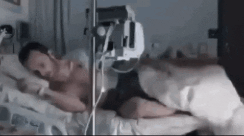 a man is laying in a hospital bed with an iv in his chest .