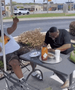 two men sit at a table with a bottle of tabasco sauce on it