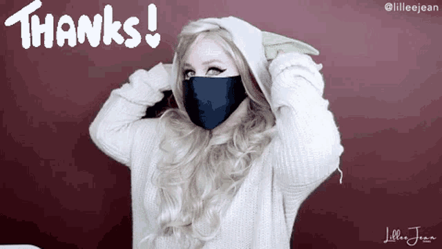 a woman wearing a black mask and a white sweater says thanks