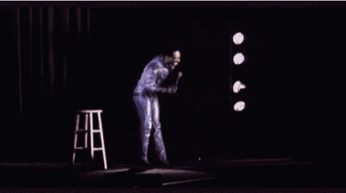 a man in a blue suit is standing on a stage with a microphone in his hand