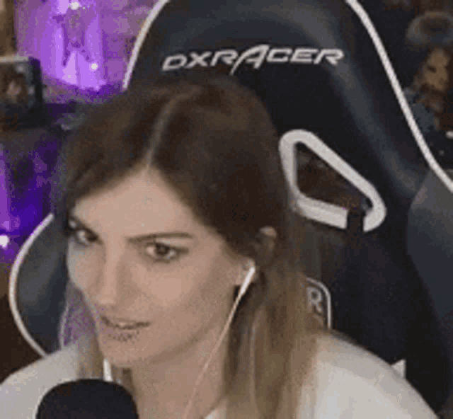 a woman is sitting in a dxracer chair with a microphone and headphones .