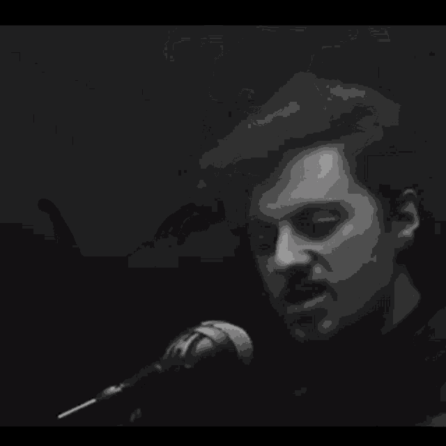 a man playing a guitar and singing into a microphone