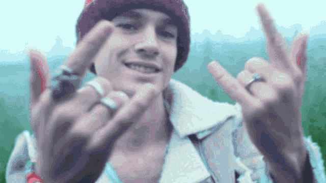 a young man wearing a beanie and a jacket is giving the middle finger