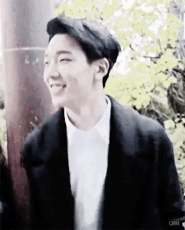 a young man wearing a white shirt and a black jacket is smiling .