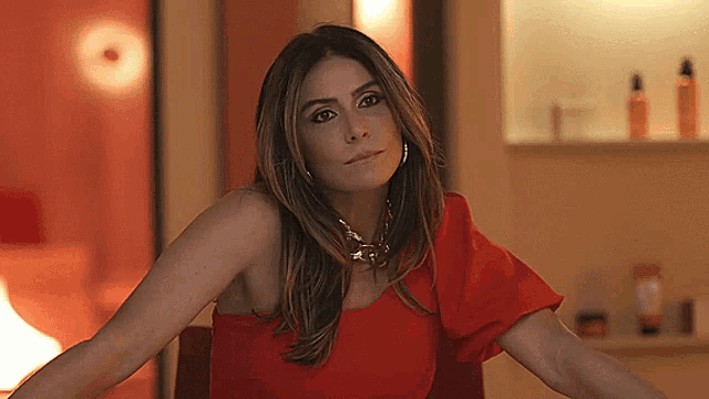 a woman in a red dress is sitting with her arms crossed