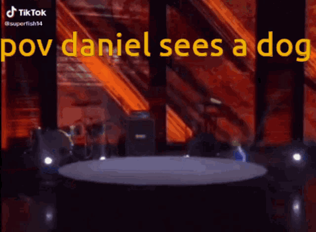 a boy in a blue suit is standing on a stage with the words pov daniel sees a dog on the screen behind him .