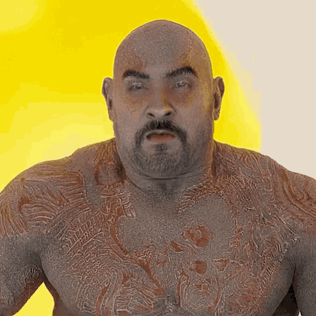 a bald man with a beard has a tattoo on his chest