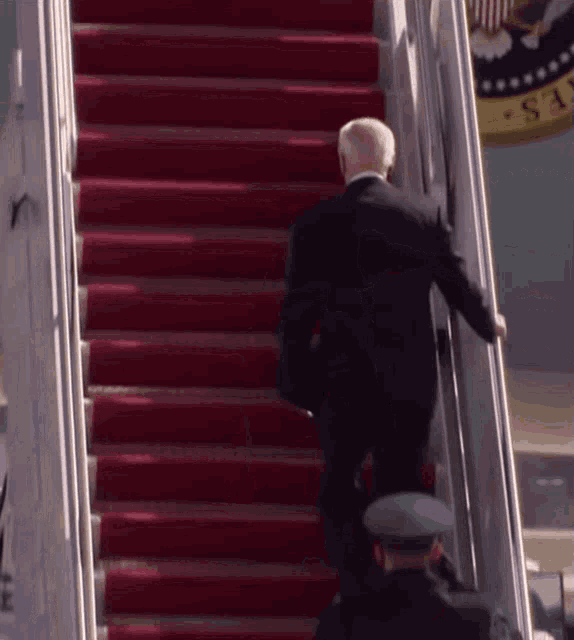 a man in a suit is walking up the stairs