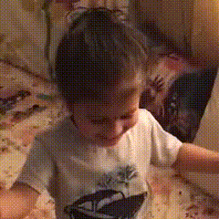 a little boy wearing a shirt with a boat on it is sitting on the floor